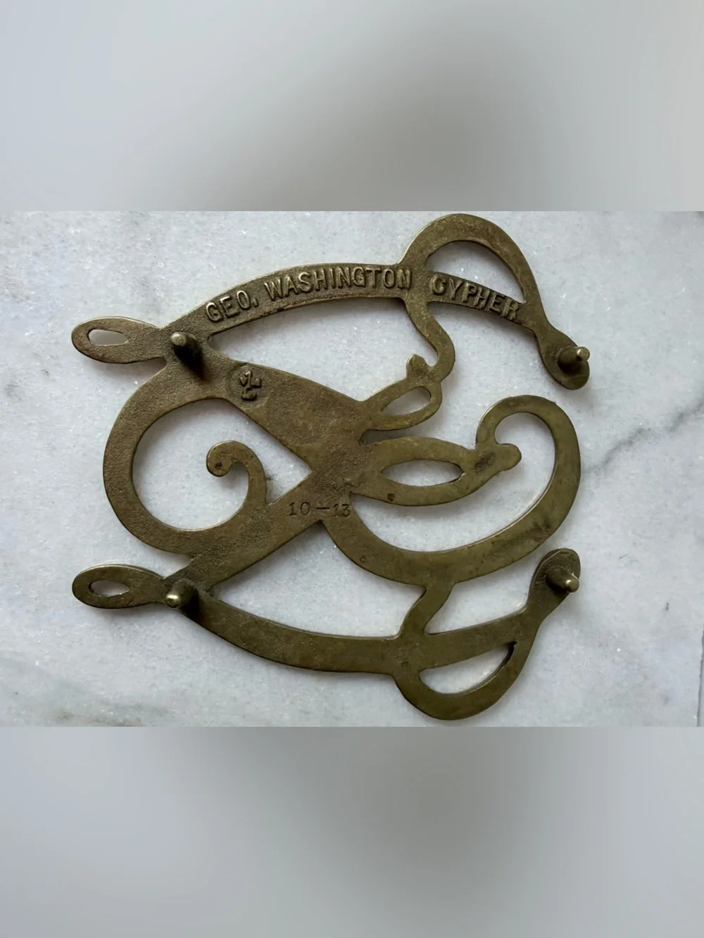 George Washington Cypher solid brass trivet, likely by Virginia Metalcrafters.